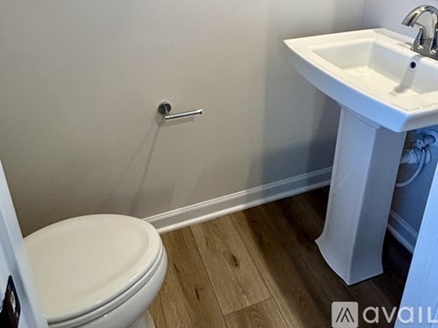 A white toilet sits next to a white sink in a small bathroom.