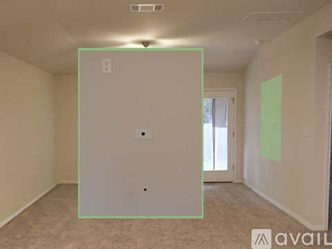 A room with a carpeted floor and a window with a view of trees outside.