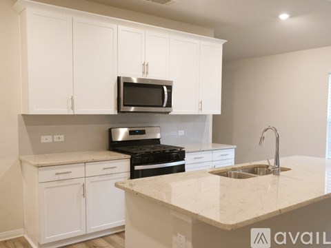 A kitchen with white cabinets and a marble countertop.
