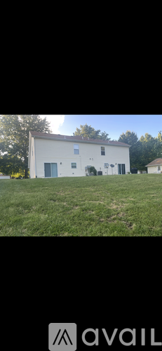 A white building with a black door is situated in a grassy area.