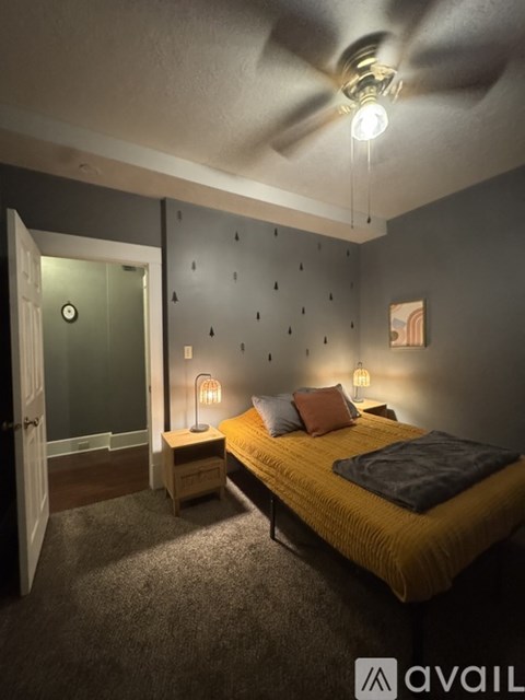 A bedroom with a bed, nightstand, and wall decorations.