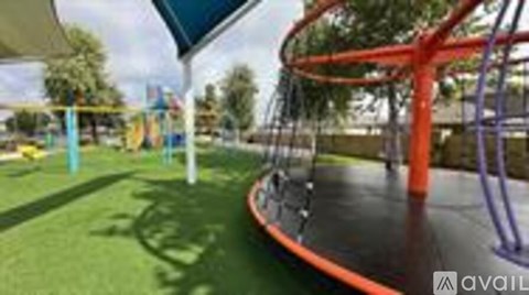A playground with a red and orange swing set.