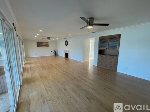 A spacious room with wooden flooring and a ceiling fan.