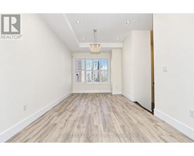 A spacious room with wooden flooring and a large window.