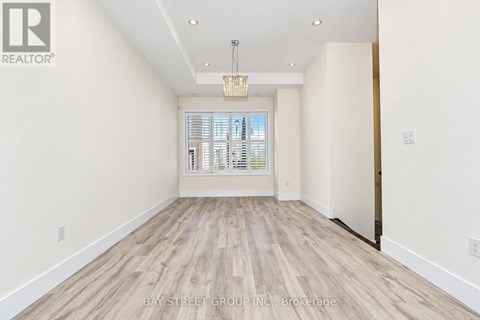 A spacious room with wooden flooring and a large window.