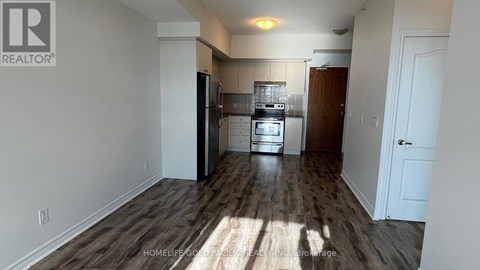 A kitchen with white walls and a wooden floor.