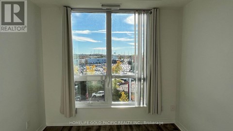 A room with a window showing a view of a street with cars and buildings.
