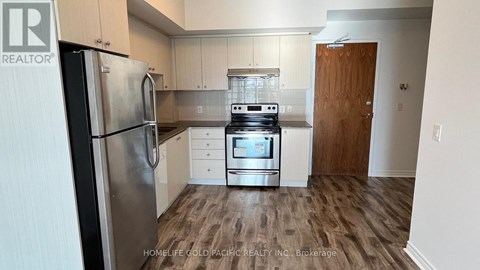 A kitchen with a refrigerator, oven, and cabinets.