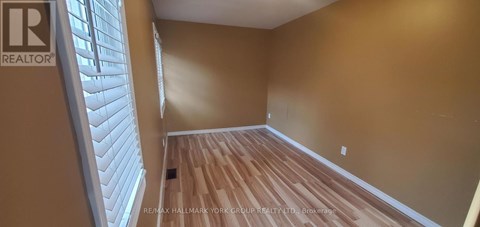 A room with wooden flooring and a window with blinds.