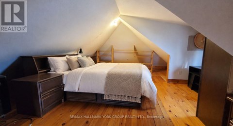 A bedroom with a bed, nightstand, and wooden floors.