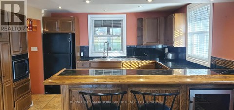 A kitchen with a black refrigerator and wooden cabinets.
