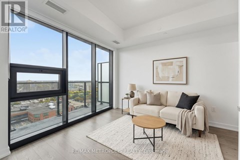 A living room with a couch, a coffee table, and a large window overlooking a cityscape.