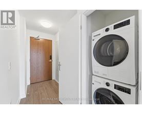 A white washing machine and dryer stacked on top of each other in a small room.