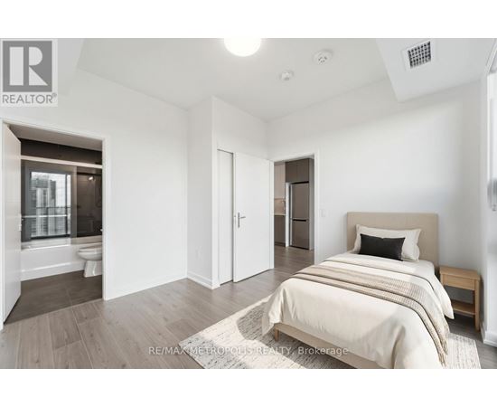 A bedroom with a bed, nightstand, and a window with a view of a balcony.