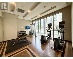 A gym with a row of stationary bikes and a flat screen TV.