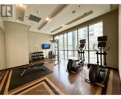 A gym with a row of stationary bikes and a flat screen TV.