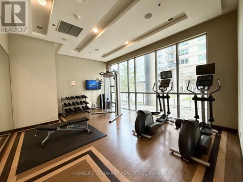A gym with a row of stationary bikes and a flat screen TV.
