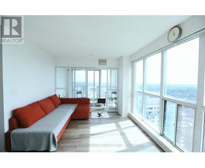 A living room with a red couch and a large window overlooking the city.