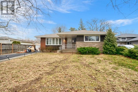 A house with a brown roof and a white fence is surrounded by a grassy area.