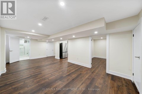 A spacious room with wooden floors and white walls.