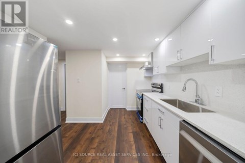 A kitchen with a stainless steel refrigerator and wooden floors.