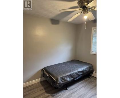 A bedroom with a bed, ceiling fan, and light fixture.