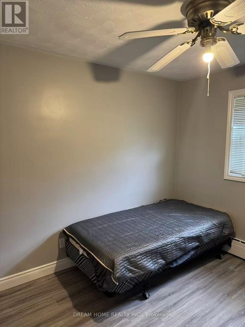 A bedroom with a bed, ceiling fan, and light fixture.