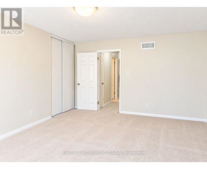 A bedroom with a white door and carpeted floor.