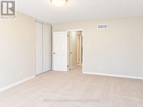 A bedroom with a white door and carpeted floor.