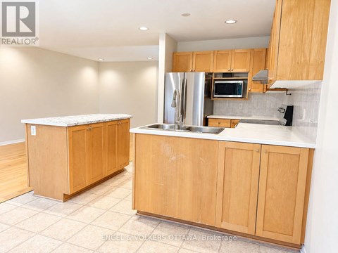 A kitchen with wooden cabinets and a stainless steel refrigerator.