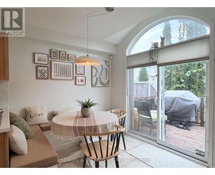 A living room with a round table and chairs, a sofa, and pictures on the wall.