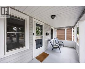 A white porch with a chair and a table.