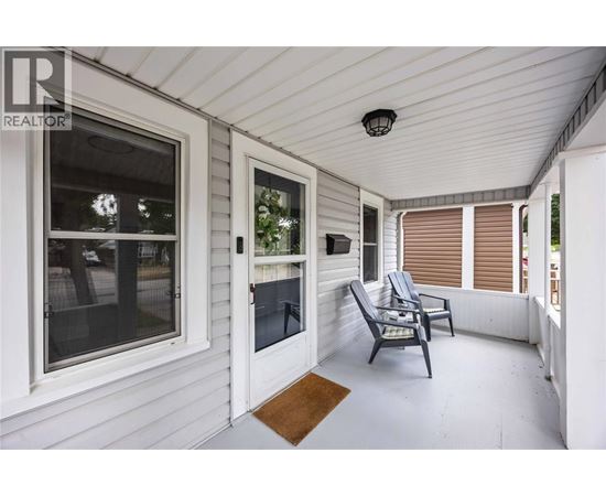 A white porch with a chair and a table.