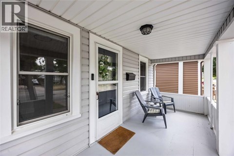 A white porch with a chair and a table.