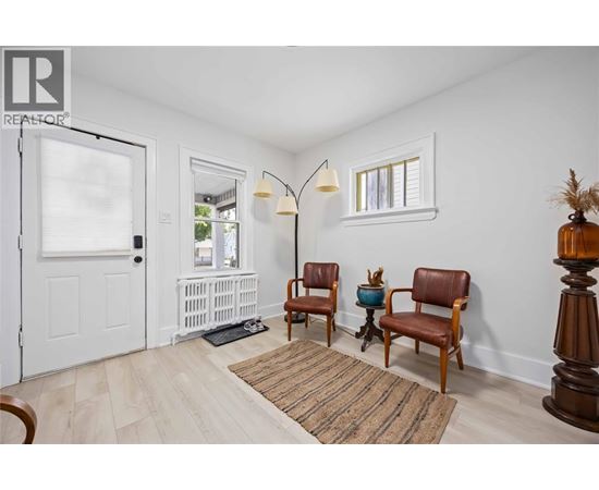 A living room with two chairs and a table with a vase on it.