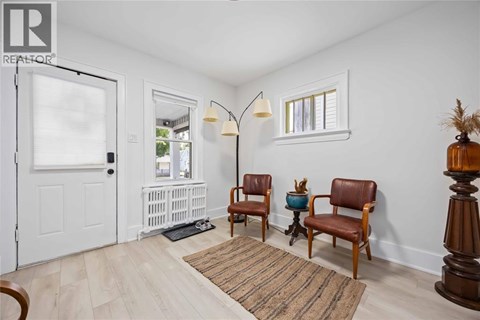 A living room with two chairs and a table with a vase on it.