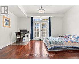 A bedroom with a bed, desk, chair, and a window with a view of a building outside.