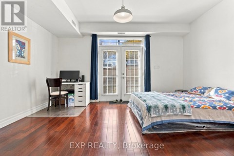 A bedroom with a bed, desk, chair, and a window with a view of a building outside.