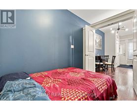 A bedroom with a bed covered in a red and gold comforter.