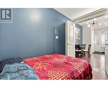 A bedroom with a bed covered in a red and gold comforter.
