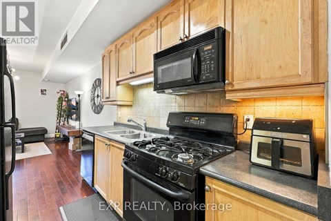A kitchen with a black stove top oven and a black microwave above it.