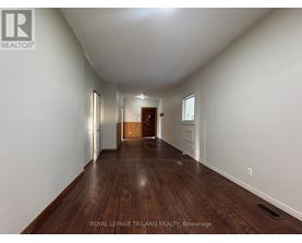 A long hallway with wood floors and white walls.