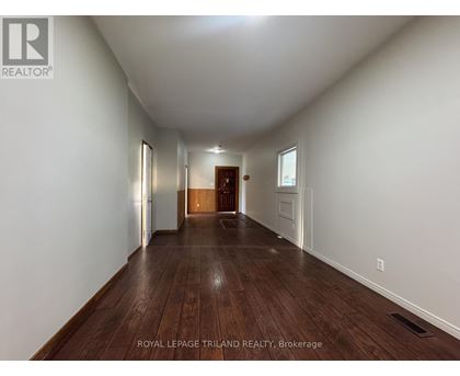 A long hallway with wood floors and white walls.