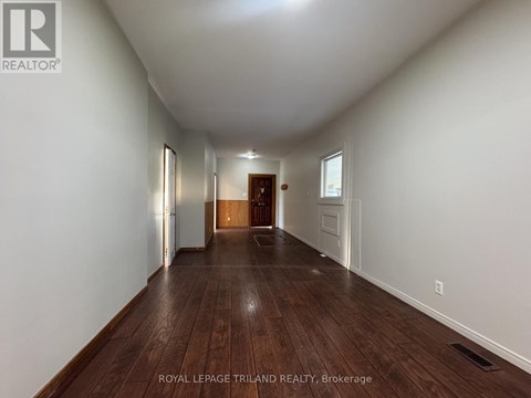 A long hallway with wood floors and white walls.