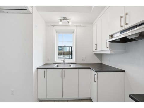 A kitchen with white cabinets and a black countertop.