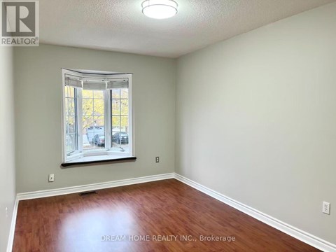 A room with a window and wooden flooring.