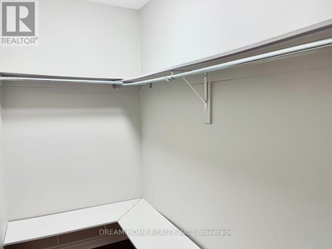 A white room with a bed and a brokerage sign.