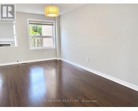 A room with wooden floors and a window showing a view of a backyard.
