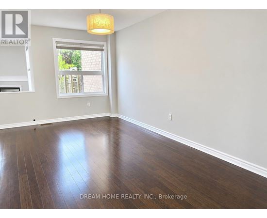 A room with wooden floors and a window showing a view of a backyard.