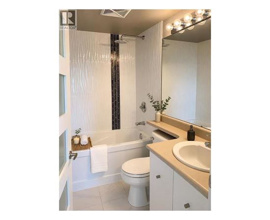 A white bathroom with a toilet, sink, and a shower.